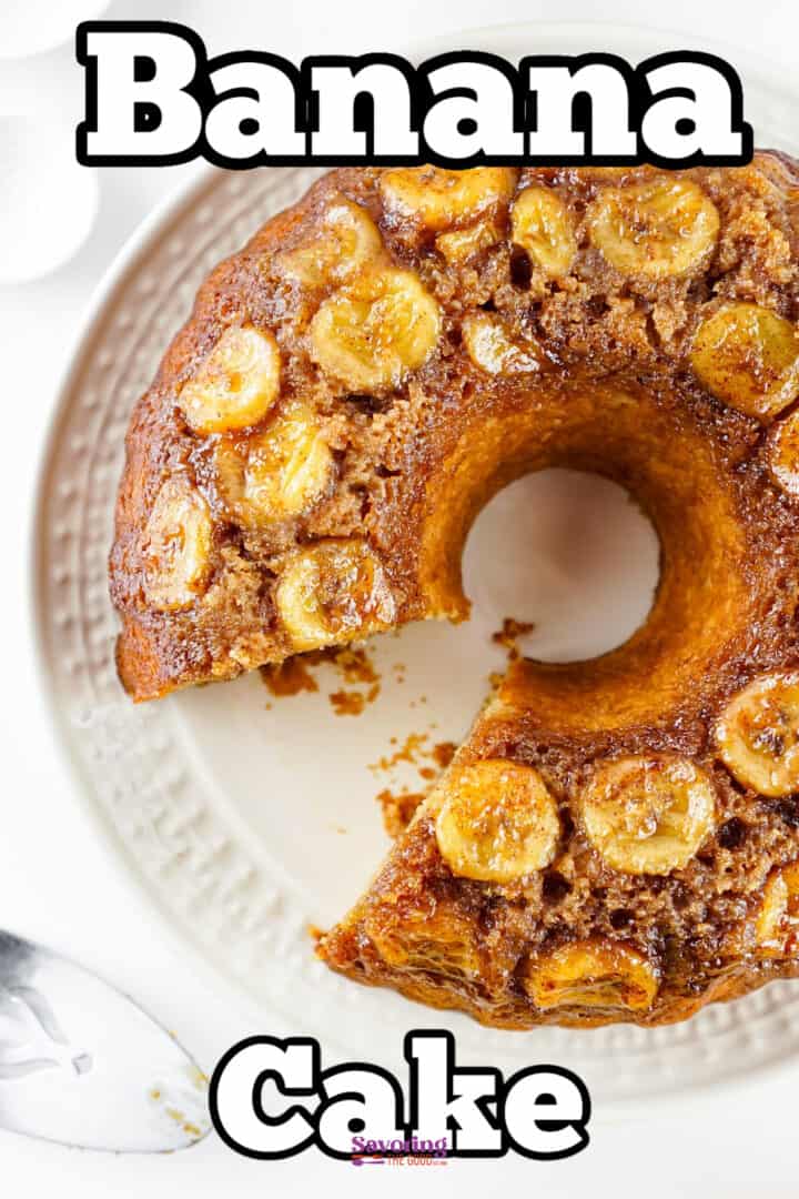A round banana cake with banana slices on top, placed on a white plate, with one slice missing; text reads "Banana Cake.