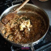 Chopped onions sautéing in a pan with brown sugar, butter, and herbs, stirred with a wooden spoon on a stovetop.