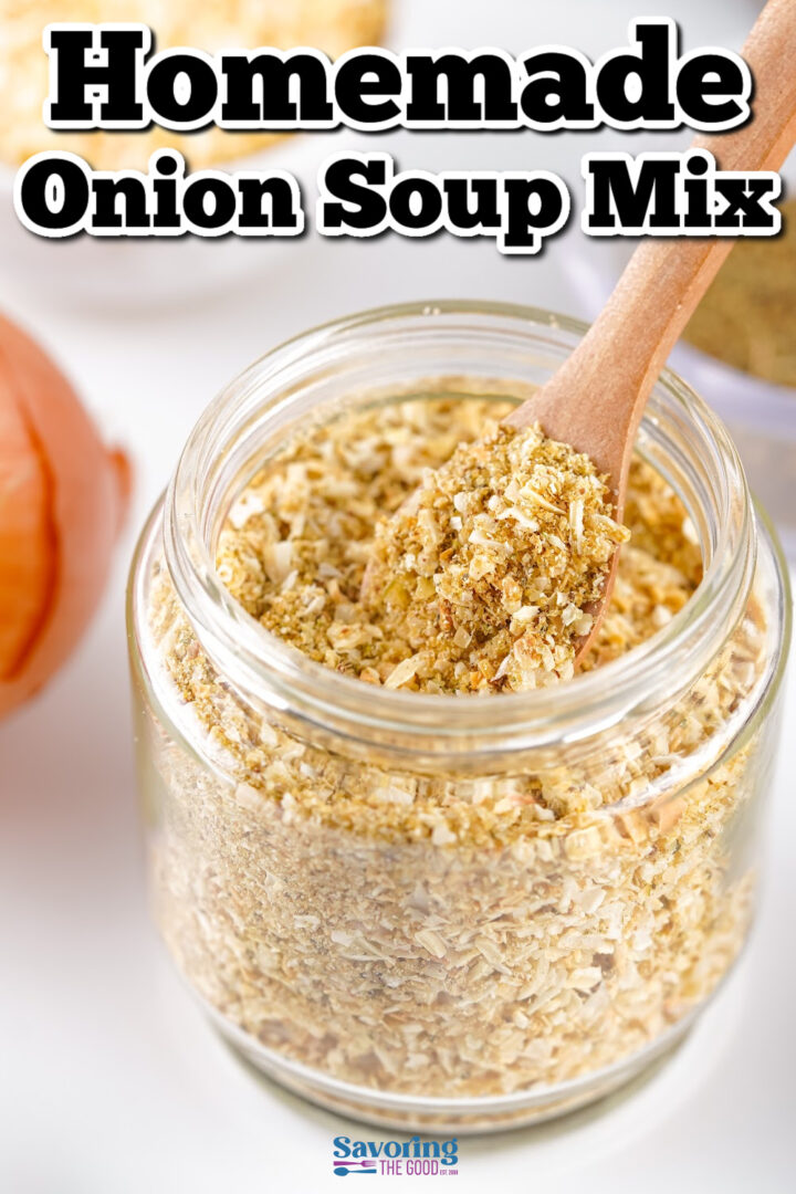 A glass jar filled with homemade onion soup mix, with a wooden spoon inside. An onion is visible in the background.