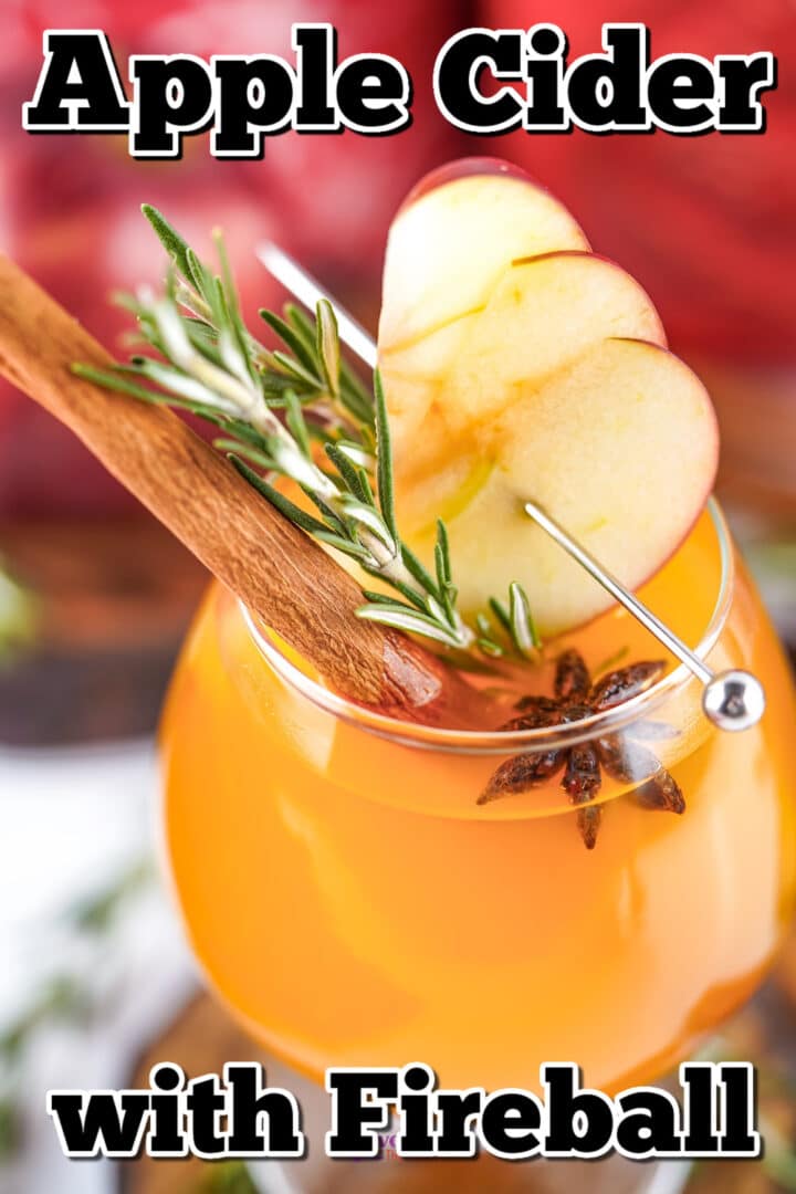 A glass of apple cider garnished with apple slices, rosemary, a cinnamon stick, and star anise, with text reading “Apple Cider with Fireball.”.