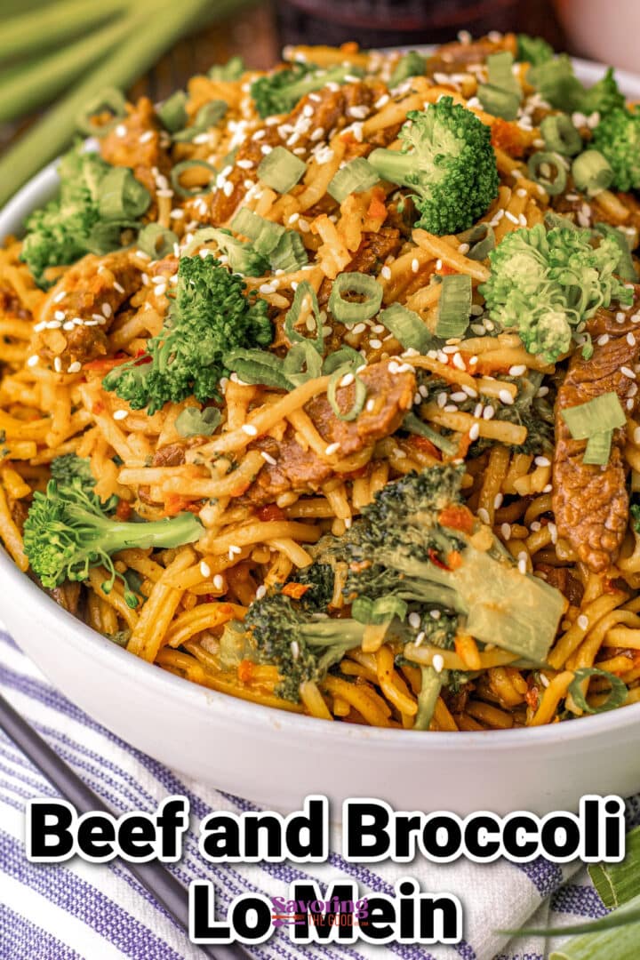 A bowl of beef and broccoli lo mein garnished with sesame seeds and chopped green onions.