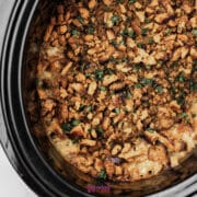 Stuffing and chicken crock pot casserole topped with browned, crumbled bread or crackers and chopped herbs in a slow cooker.
