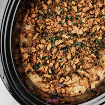Stuffing and chicken crock pot casserole topped with browned, crumbled bread or crackers and chopped herbs in a slow cooker.