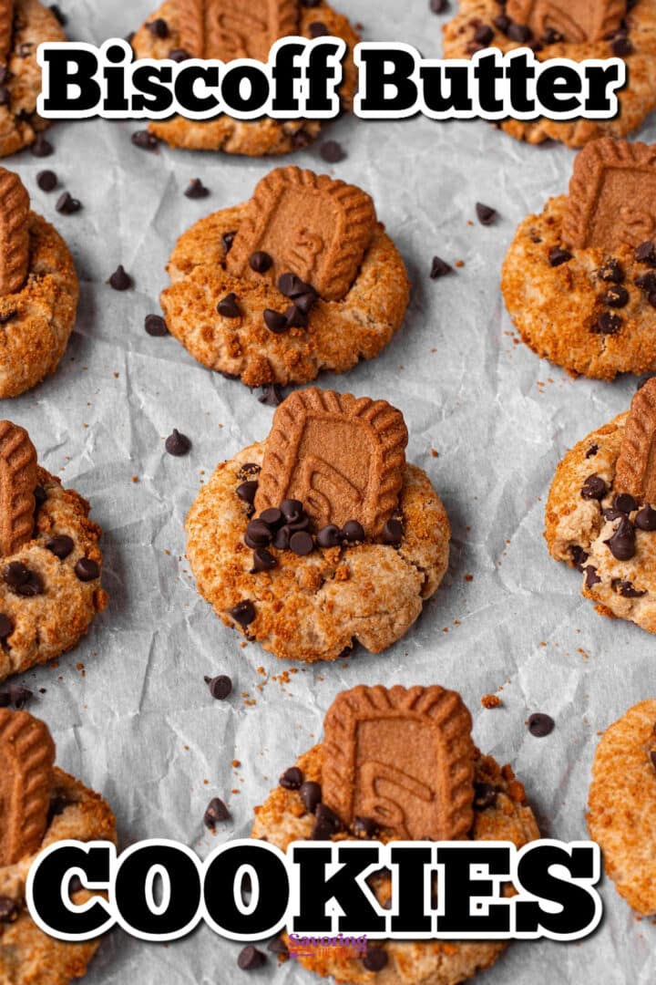 Biscoff butter cookies topped with Biscoff biscuit pieces and chocolate chips, arranged on parchment paper.