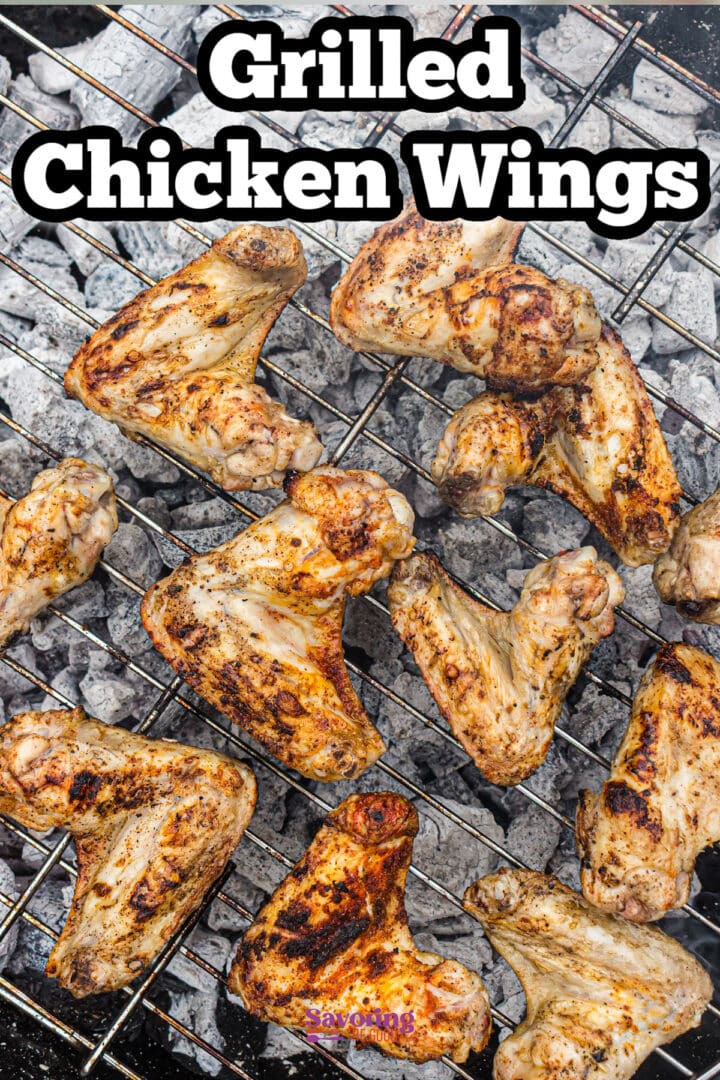 Grilled chicken wings cooking on a metal grate over hot charcoal, viewed from above.