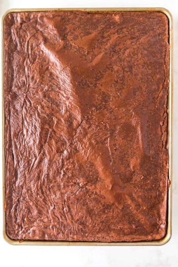 A large rectangular baking sheet filled with chocolate frosted Sheet Pan Brownies, viewed from above, showcasing a rich and decadent dessert.