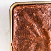 A close-up of a metal baking pan filled with freshly baked Sheet Pan Brownies, showing a cracked, glossy surface.