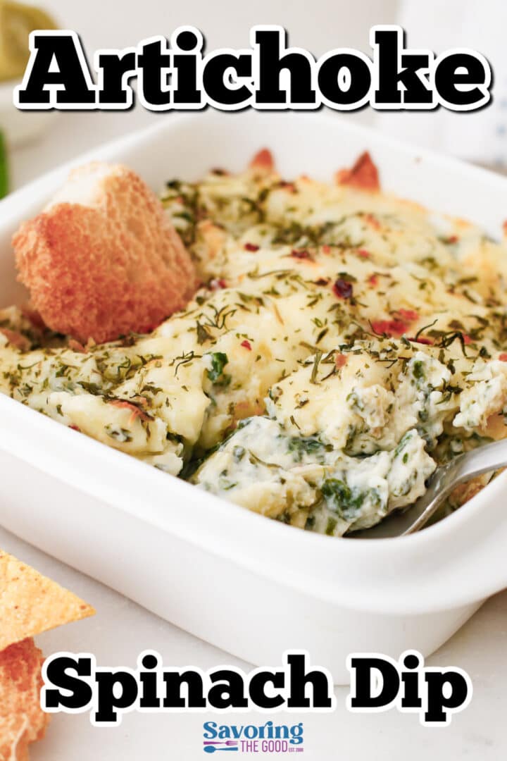 A baked artichoke spinach dip in a white dish, topped with herbs, with a piece of bread dipped in and a spoon at the side. Text reads "Artichoke Spinach Dip.