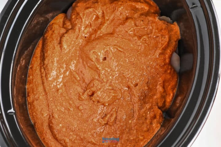 Sauce spread evenly inside a black slow cooker, ready for baking or cooking a delicious slow cooker chicken tikka masala.