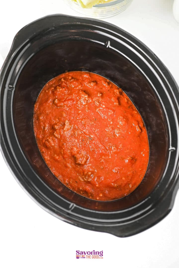 A slow cooker filled with rich red tomato sauce and ground meat, viewed from above-perfect for making a hearty lazy lasagna.