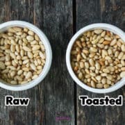 Two white bowls on a dark wooden surface, one containing raw pine nuts and the other containing toasted pine nuts, labeled