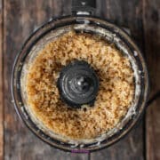 Food processor filled with finely chopped Parmesan cheese and nuts.