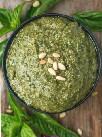 A bowl of basil pesto topped with pine nuts.